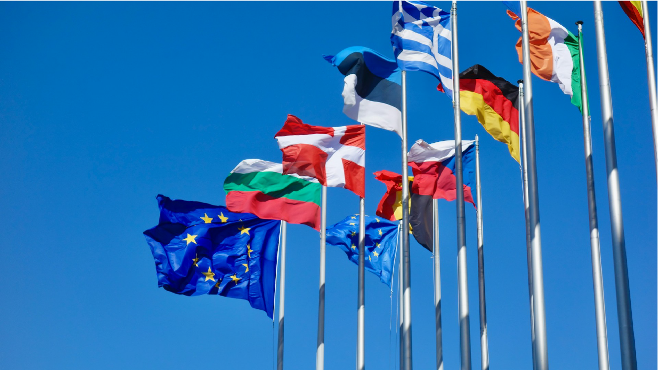 Multiple European flags waving against a clear blue sky, symbolizing the diversity of the European Union member states.