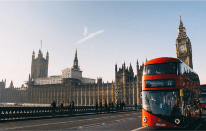 Red double-decker bus crossing Westminster Bridge with the Houses of Parliament in the background, London, UK