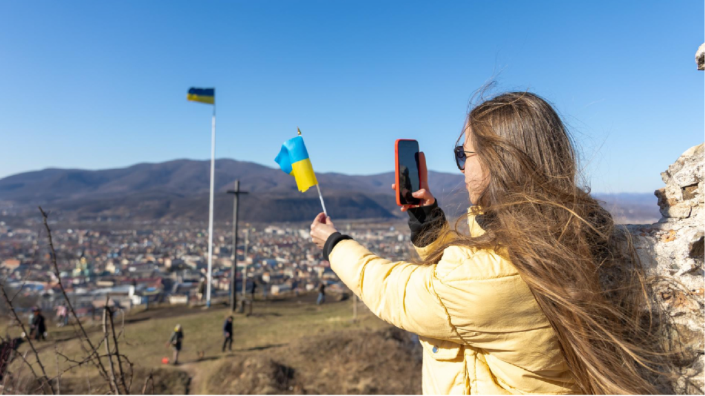 Ukrainian Woman using smartphone to capture flags, showcasing global digital communication